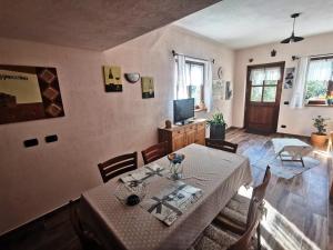 una sala da pranzo con tavolo, sedie e TV di Casa Bella Vista a Villar San Costanzo