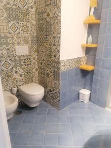 y baño de azulejos azules con aseo y ducha. en Casetta Russo, en Meta