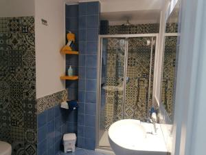 y baño de azulejos azules con lavabo y ducha. en Casetta Russo, en Meta