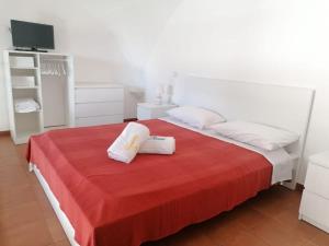 1 dormitorio con 1 cama roja y 2 toallas en Casetta Russo, en Meta