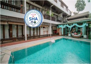 um hotel com piscina em frente a um edifício em Baan Huenphen em Chiang Mai