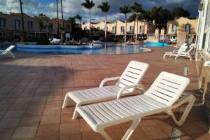 dwa białe krzesła siedzące na patio z basenem w obiekcie GLAMOUR MASPALOMAS - near MELONERAS w mieście San Bartolomé