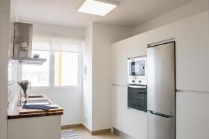 a white kitchen with a refrigerator and a window at Stylish City Vacation Gran Canaria in Las Palmas de Gran Canaria