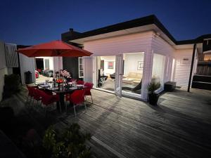 a wooden deck with a table and an umbrella at Ocean Front East End Beach House in New Plymouth