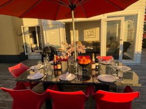 a dining table with red chairs and an umbrella at Ocean Front East End Beach House in New Plymouth +31 photos