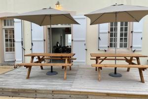 2 Picknicktische und 2 Sonnenschirme auf einer Terrasse in der Unterkunft Agon-Coutainville, villa bord de mer in Agon Coutainville