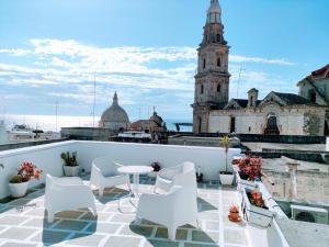 a balcony with white chairs and a table and a building at La Torre e il Mare Rooms in Monopoli