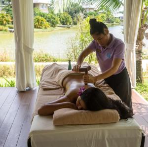 a woman laying on a bed as a girl is cutting at TheLifeCo Wellbeing Phuket Detox Center and Vegan Hotel - SHA Plus in Nai Thon Beach