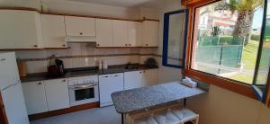 una pequeña cocina con armarios blancos y una ventana en Precioso apartamento en luanco junto a la playa, en Luanco