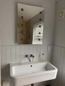 Un lavabo blanco en un baño con espejo. en Wonderful Home and parking, pets allowed, en Tenby 12 fotos más