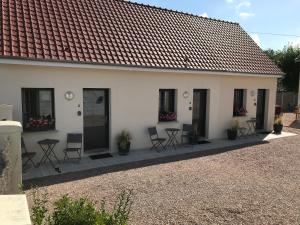 une maison blanche avec des chaises et des tables devant elle dans l'établissement La Rose des Vents, au Crotoy