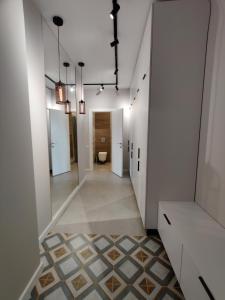 a hallway with white walls and a tile floor with a toilet at Wood Apartment in Odesa