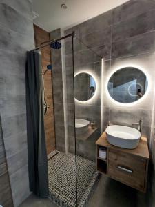 a bathroom with a sink and a shower with two mirrors at Wood Apartment in Odesa