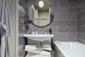 a bathroom with a sink and a tub and a mirror at Aparthotel Adagio Paris Suresnes Longchamp in Suresnes +63 photos