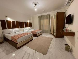 una camera d'albergo con due letti e una televisione di Kemet Apartment luxor a Luxor