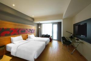 a hotel room with two beds and a flat screen tv at Novotel Pekanbaru in Pekanbaru