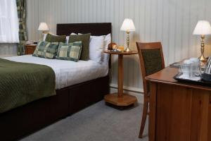 a bedroom with a bed and a desk with two lamps at Old Hunstanton Le Strange Arms Hotel in Hunstanton