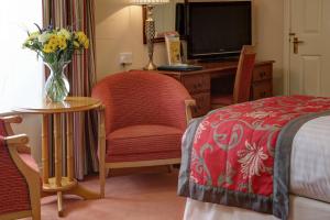 a bedroom with a bed and a vase of flowers on a table at Old Hunstanton Le Strange Arms Hotel in Hunstanton