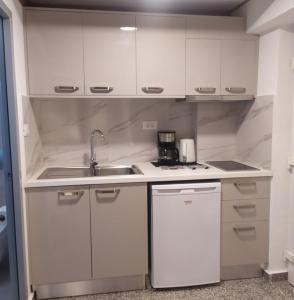 a small kitchen with white cabinets and a sink at Nicolas Apartments in Ierapetra