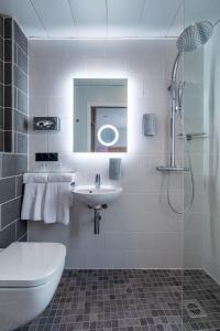 La salle de bains blanche est pourvue d'un lavabo et d'une douche. dans l'établissement Hôtel de Bellevue Paris Gare du Nord, à Paris