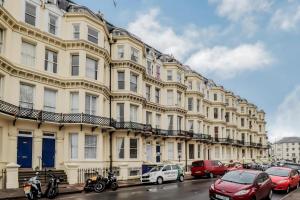 un grand bâtiment avec des voitures garées devant lui dans l'établissement 3 Queens Gardens Sea View Apartment, à Eastbourne