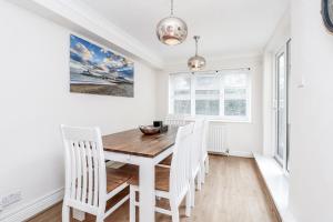 a dining room with a wooden table and white chairs at 3 Queens Gardens Sea View Apartment in Eastbourne
