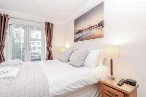 1 dormitorio con cama blanca y ventana en 3 Queens Gardens Sea View Apartment en Eastbourne