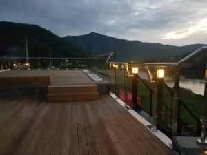 una terraza de madera con luces y una masa de agua en Tomato Pension, en Hongcheon
