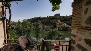 a balcony with two chairs and a view of a river at Apartamento/Casa El Puente in Toledo