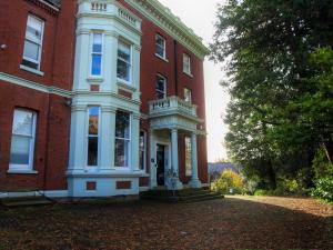 um grande edifício de tijolos vermelhos com um alpendre branco em Torrington Hall em Saint Albans