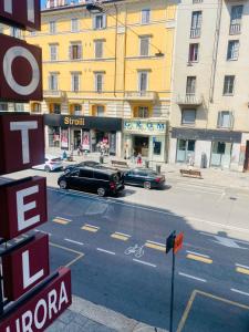 eine Straße mit zwei Autos, die vor einem Gebäude geparkt sind in der Unterkunft Hotel Aurora in Mailand