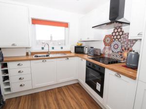 a kitchen with white cabinets and a sink at 8 Watkin Street in Conwy