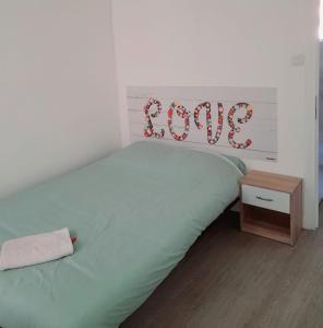 a bedroom with a bed with a love sign on it at Appartement 3 pièces lumineux au cœur du village in Saint-Martin-Vésubie