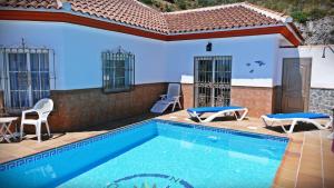 a swimming pool with chairs and a house at Castillo de la Hazalara in Cómpeta