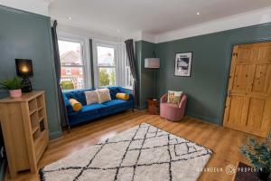 a living room with a blue couch and a window at Beautiful and Stylish 3Bedroom Flat with Parking - Beaufort Heights in Iford