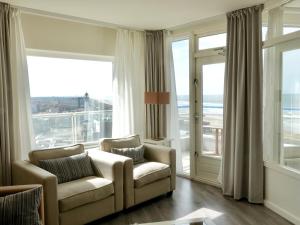 a living room with two chairs and large windows at Droomvakanties Egmond Zeezicht in Egmond aan Zee