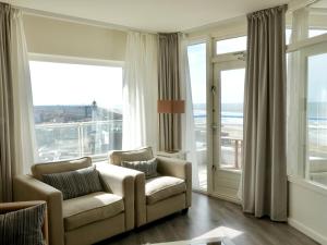 een woonkamer met 2 stoelen en grote ramen bij Droomvakanties Egmond Zeezicht in Egmond aan Zee