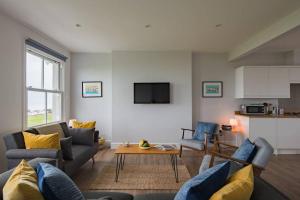 a living room with two couches and a table at The Lookout - Stunning sea view apartment in Deal