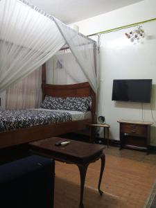 a bedroom with a bed and a tv and a table at SAFI Apartment in Mombasa