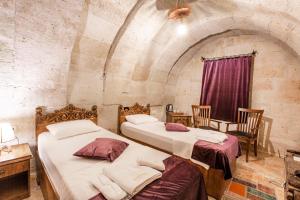 two beds in a room with a stone wall at kayadibi cave hotel in Ürgüp