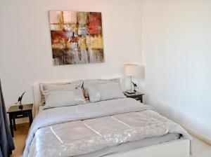 a bed in a white bedroom with a painting on the wall at Al Qudra Town Square 2 Bedroom Duplex Apartment Dubai in Dubai