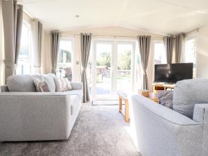 a living room with two couches and a tv at Hawthorn Lodge in Carnforth