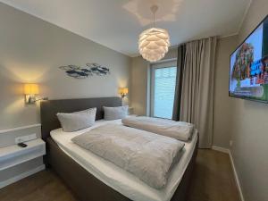 une chambre avec deux lits et un lustre dans l'établissement Tüngelstuuv Sylt, à Westerland