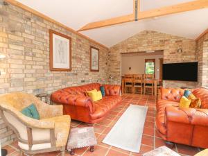 a living room with leather furniture and a brick wall at Coronation Cottage in Wisbech