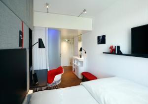 a hotel room with a white couch and a white bed at citizenM Zürich in Zurich