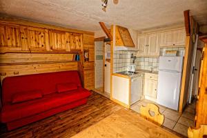 ein Wohnzimmer mit einer roten Couch in der Küche in der Unterkunft le burel la triade 4 personnes in Lanslevillard