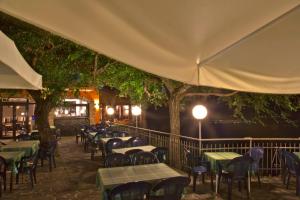 a patio with tables and chairs and trees at night at Hotel Giardinetto in San Zeno di Montagna