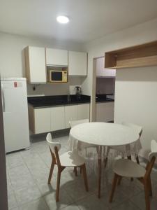 a kitchen with a table and chairs and a kitchen with a refrigerator at Casa 80m apenas 6km do Morro do Careca Natal in Natal