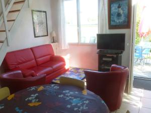 プルガヌーにあるMaison de charme à Plougasnou avec jardin clôturéの赤いソファとテレビのあるリビングルーム