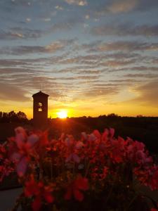 una torre del reloj con una puesta de sol en el fondo con flores en B&B RoofTop51, en Rímini